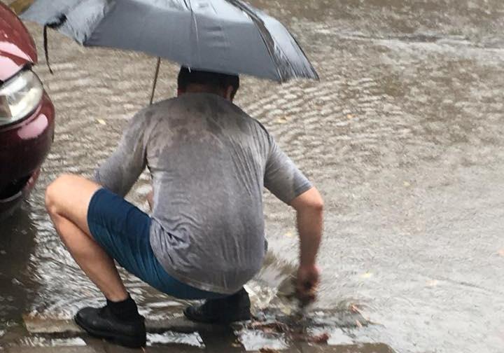 Під час зливи у Львові чоловік руками чистив каналізацію. Фото Надії Затварницької.